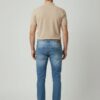 Muški model nosi svetlo plave slim fit farmerke- slika pozadi