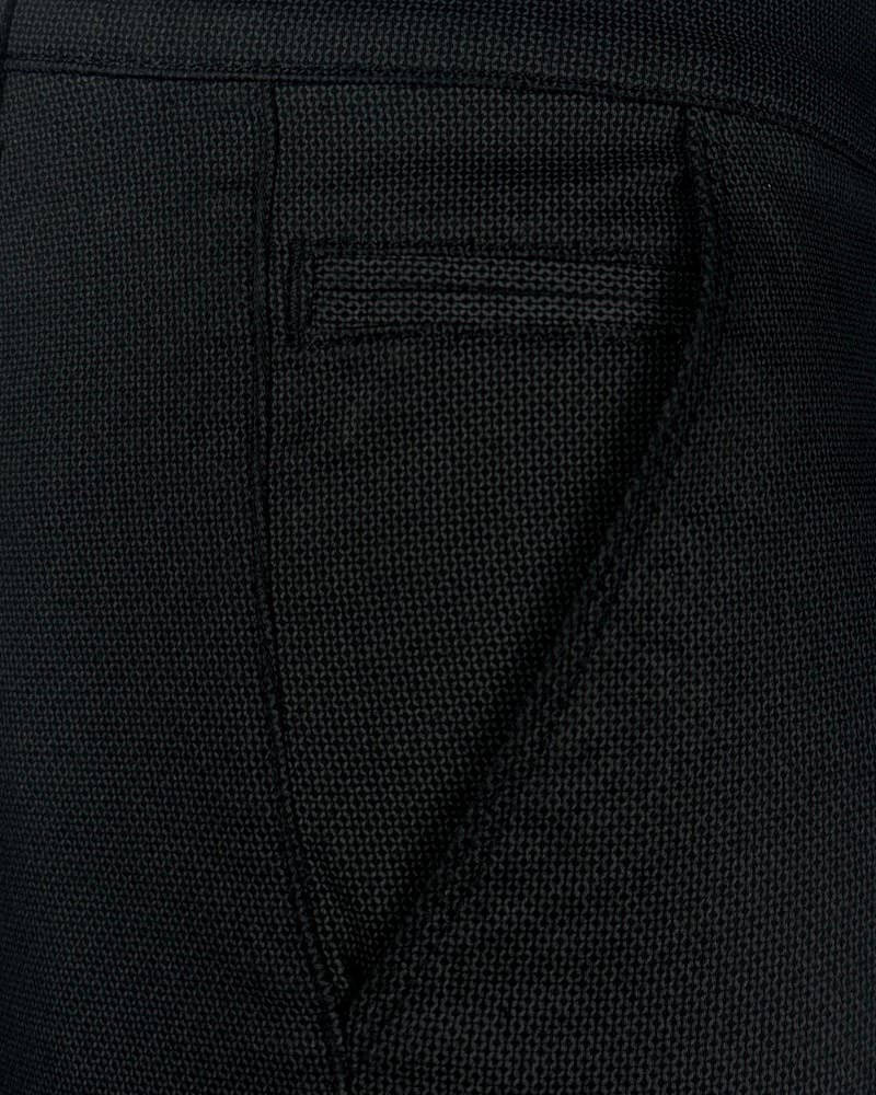 Detalj elegantnih muških pantalona sa teksturom, regular fit kroja, crne boje. Tekstura tkanine se jasno vidi.