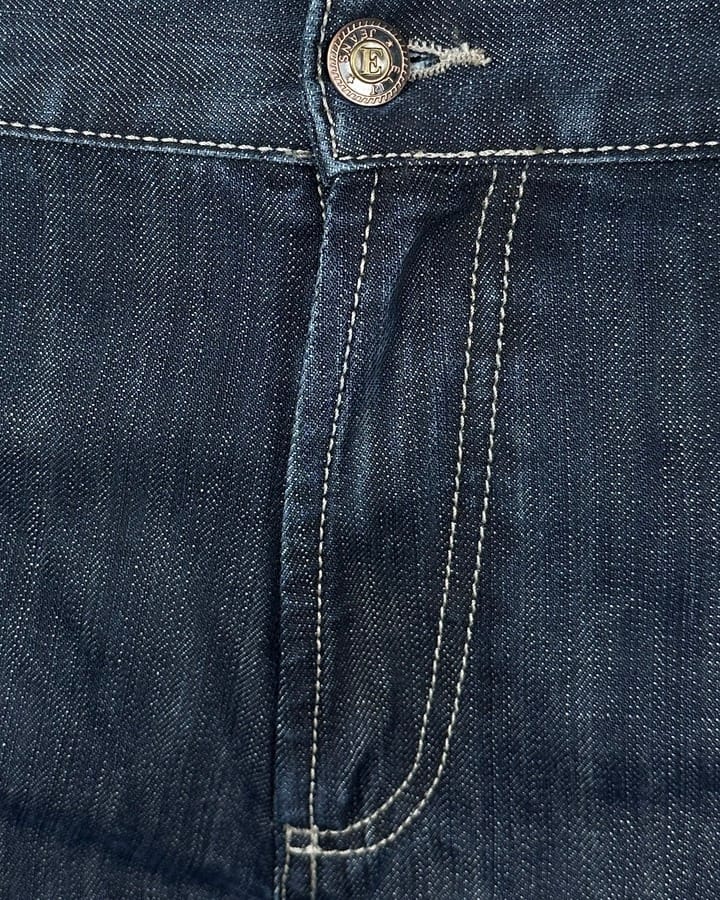 Detaljan prikaz regular fit farmerica za visoke, produžena nogavica, tamni teksas sa belim štepovima.